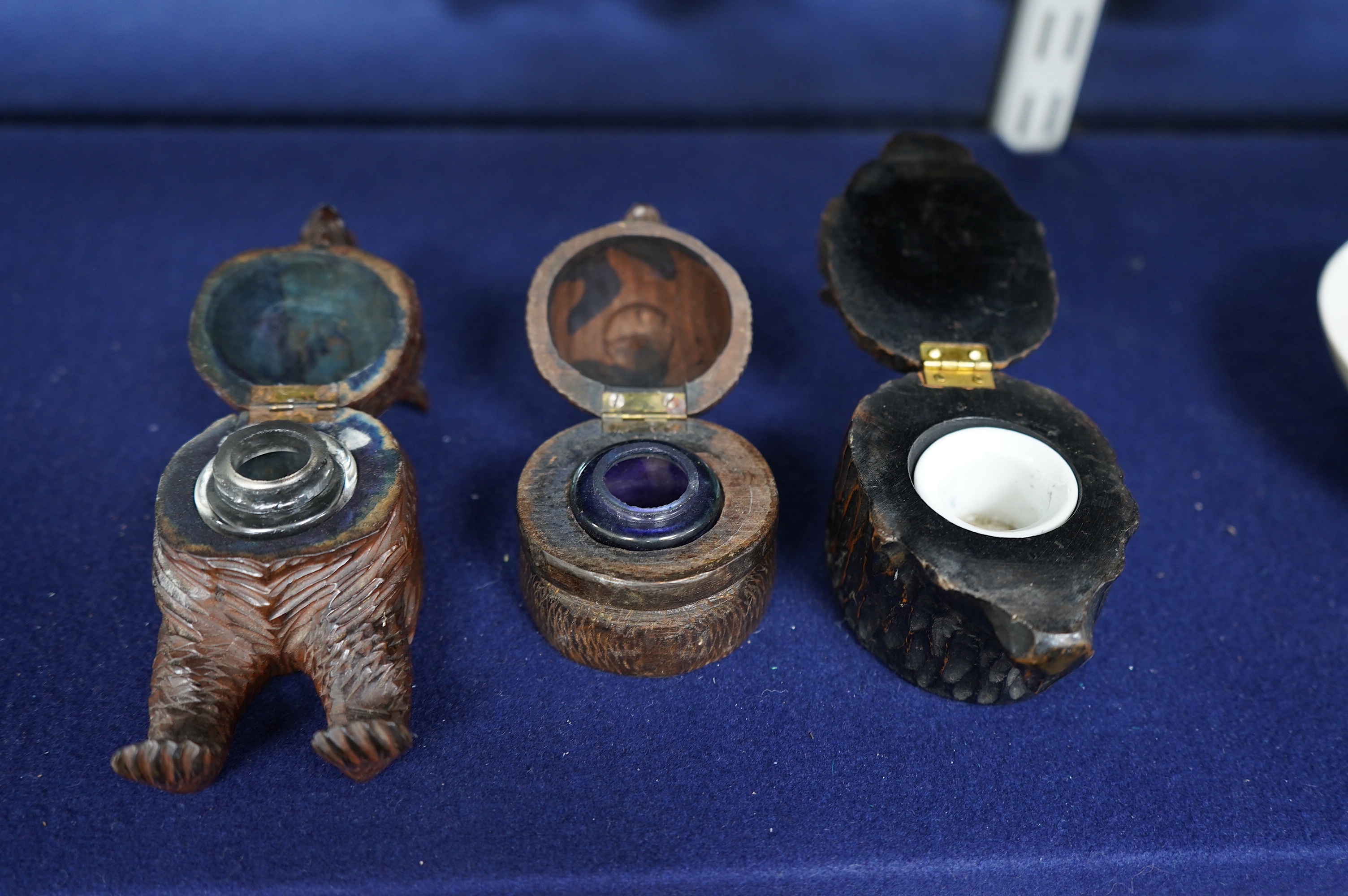 Three Black Forest carved wood novelty inkwells with glass and ceramic liners, one in the form of a lion, largest 9cm high. Condition - fair